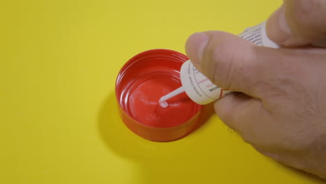 Preparing-a-bait-by-putting-a-liquid-poison-gel-over-a-red-bottle-cap-with-a-syringe