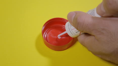 preparing a bait by putting a liquid poison gel over a red bottle cap with a syringe