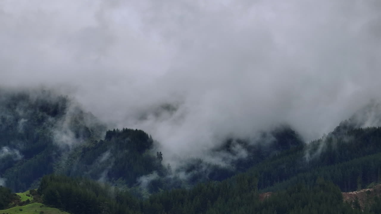 Drone Shot of Rain Clouds Moving Over Heavily Forested Mountain Range, New Zealand