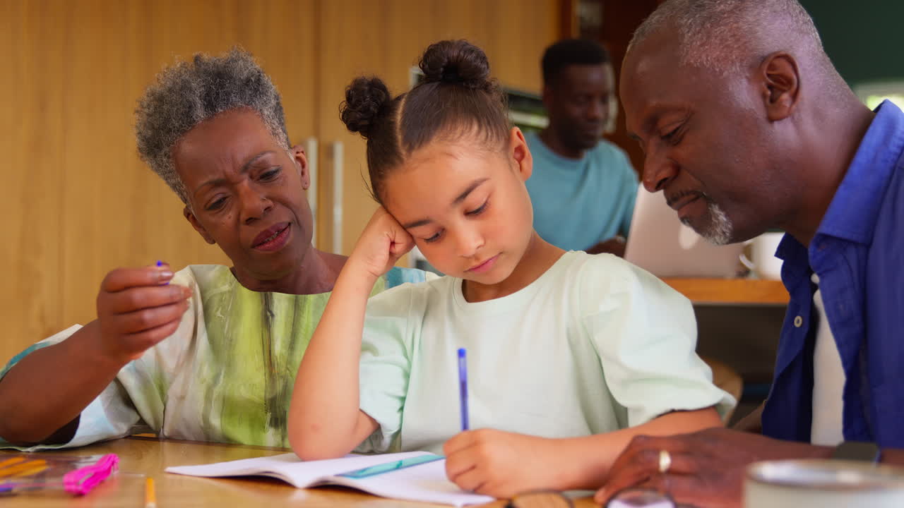Multi-Generation Family With Grandparents Helping Granddaughter With School Homework At Home