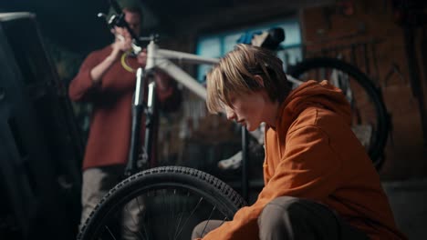 Father foreman and his son assistant work on bicycle repair in workshop. Father-Son Bonding: The Joy of Bike Repair