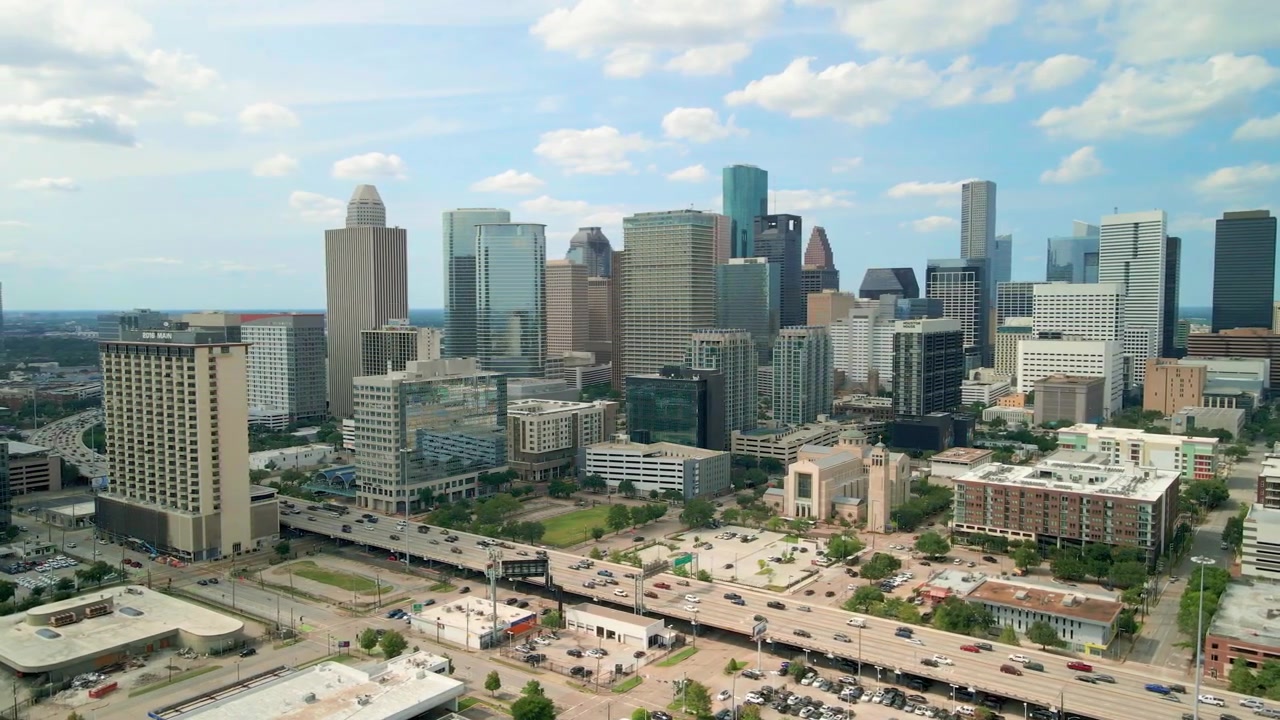 Vista aerea con drone dello skyline del centro di Houston mentre la telecamera ruota lentamente da sinistra a destra, mostrando moderni grattacieli e torri per uffici sotto nuvole drammatiche di giorno a Houston, Texas