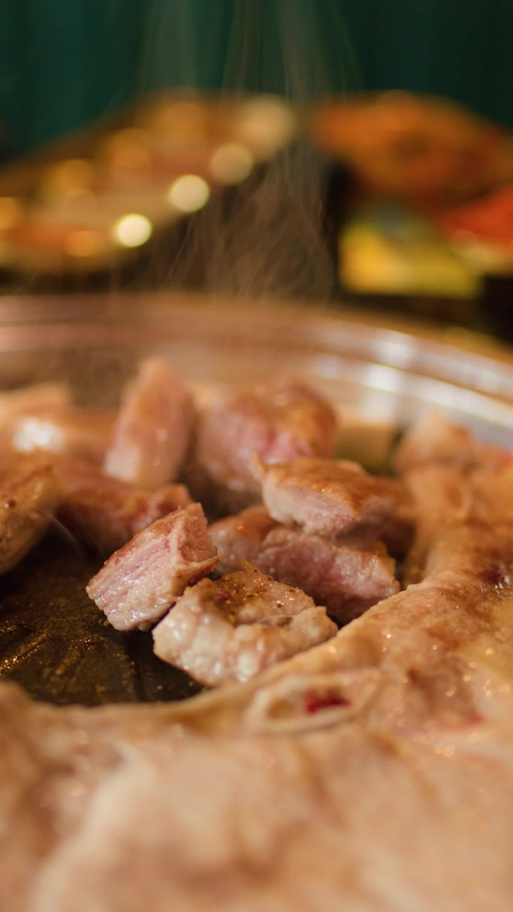 Daging babi samcan yang diiris sedang dipanggang di atas barbekyu Korea, tampilan makro, uap mengepul, bumbu ditaburkan, pencahayaan hangat.