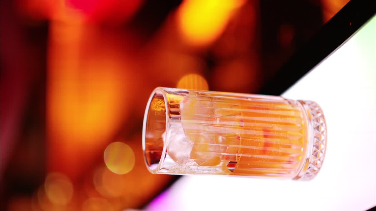 Barman che prepara cocktail con whisky alcolico al bar di notte con luci al neon rosse, slow motion verticale