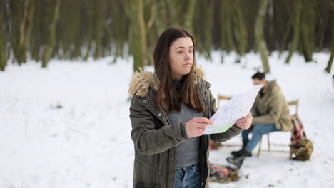 Mujer-Caucásica-Comprobando-El-Mapa-En-Busca-De-Direcciones-En-Un-Bosque-Nevado.