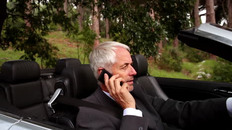 un hombre de negocios al teléfono en su coche descapotable.