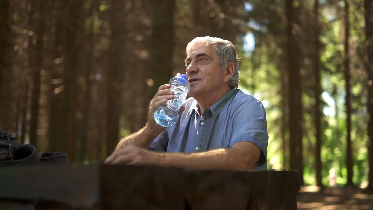 Senior man drinking water in the forest