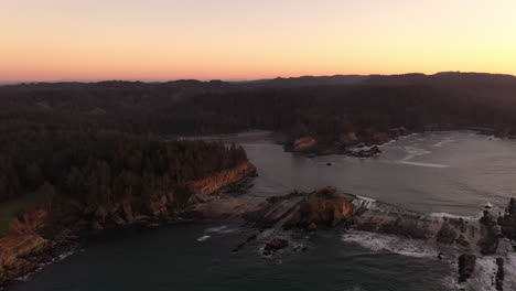 Isla-Qochyax,-Bahía-De-La-Puesta-Del-Sol-Y-Faro-Del-Cabo-Arago-En-La-Costa-De-Oregon,-Antena-Después-De-La-Puesta-Del-Sol-Al-Atardecer