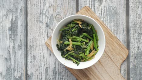 top view of bowl with cooked spinach on table