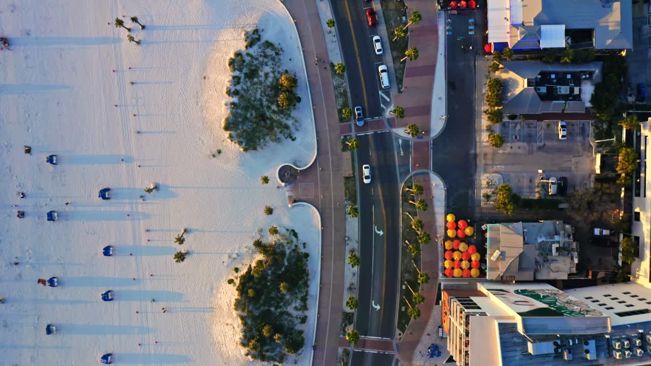 From above, Clearwater Beach reveals its organized beachfront with umbrellas on white sand, resort pools, and the palm-lined promenade separating the shoreline from the city