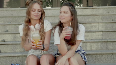 two women friends enjoying drinks on stairs