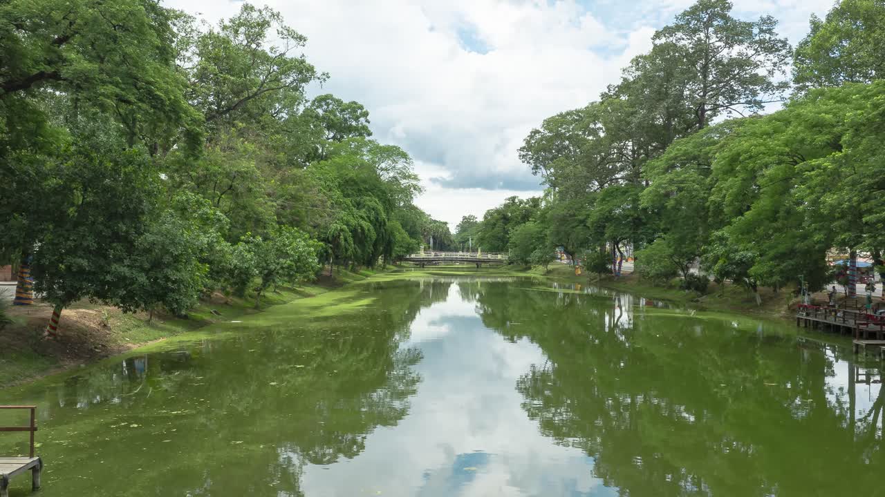 Timelapse of reflected waterway in Siem Reap framed by lush green trees