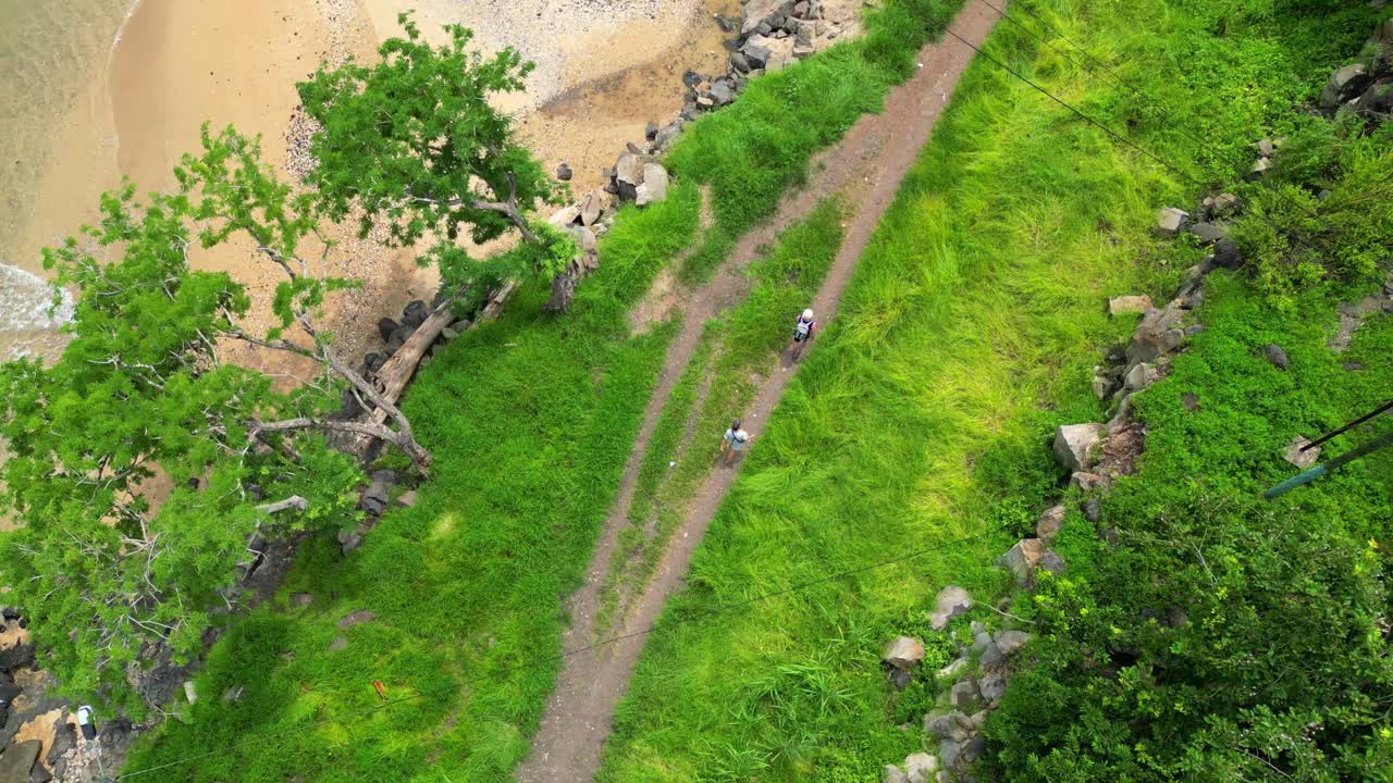 Seen from above a couple walking on a dirt path along the coast with the beach next to it São Tomé,Africa