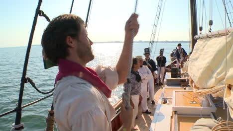 a man climbs the mast of a 19th century tall ship in this historical reenactment