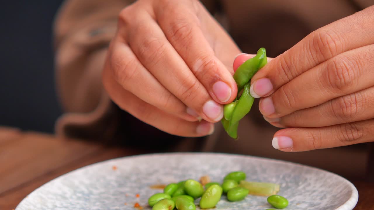 Close-up of Hands Peeling Fresh Edamame Pods