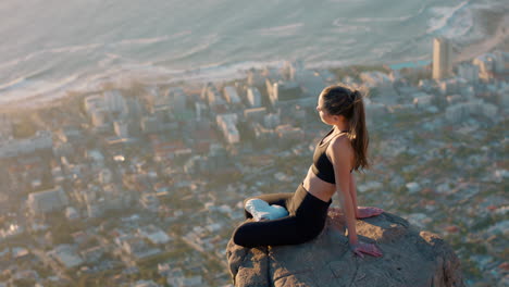 healthy woman on mountain top looking at calm view of ocean at sunset girl sitting on edge of cliff enjoying freedom contemplating journey