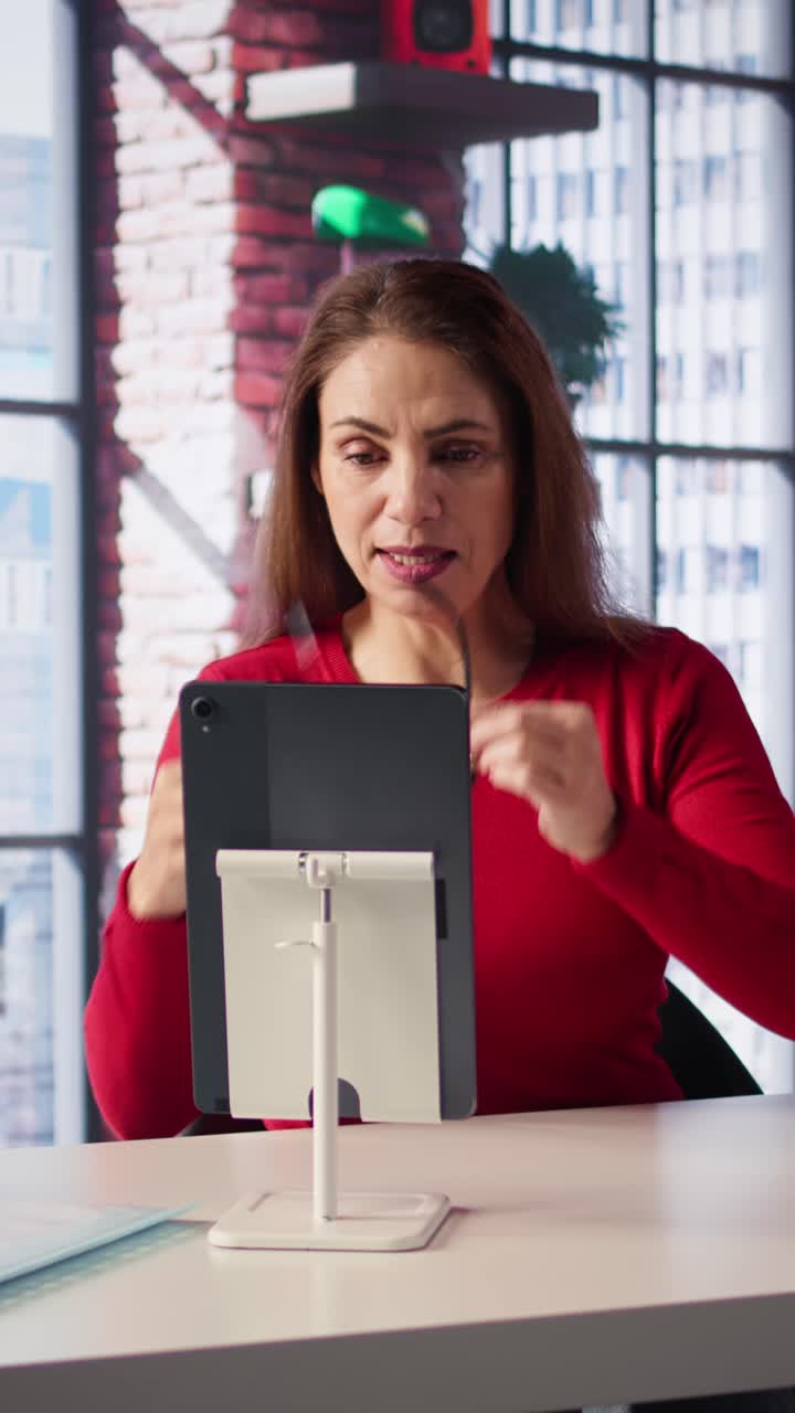Vertical Video Focused woman smiling and waving during a web conference at her home