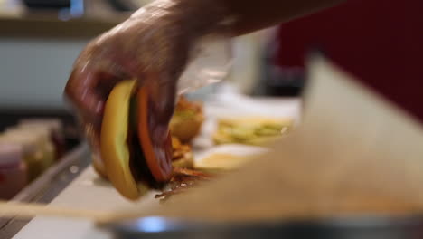 bacon being added to a chicken sandwich in the kitchen of a fast food restaurant.