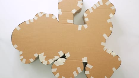 hand touches taped cardboard piñata structure on white surface ready for decoration