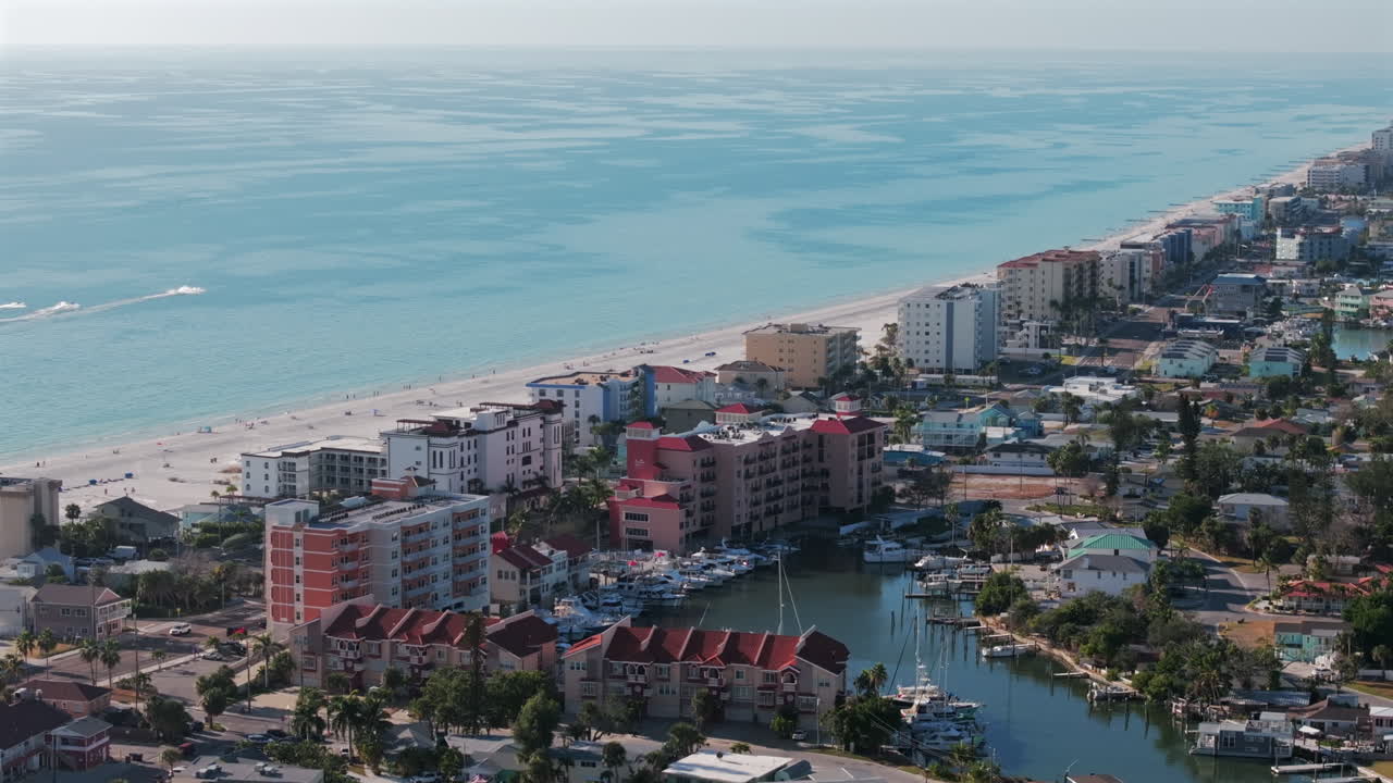Sweeping aerial drone footage of Madeira Beach showing Jack's Boat Basin marina, waterfront homes with docks, Gulf Boulevard facing North, and beachfront hotels along Florida's scenic Gulf Coast