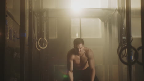 man working out in a gym with ropes and barbell