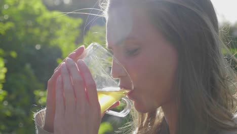 girl sips refreshing tea from glass outside on sunny day, close-up