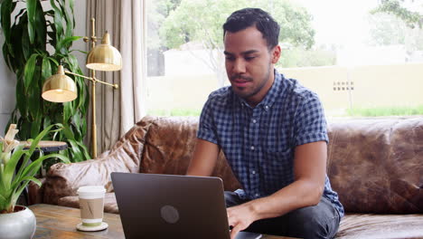 joven hispano usando una computadora portátil en una cafetería