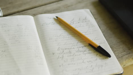 Close-up-pen-and-diary-book-with-small-illegible-writing-on-wood-desk