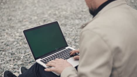 man working on laptop on a beach