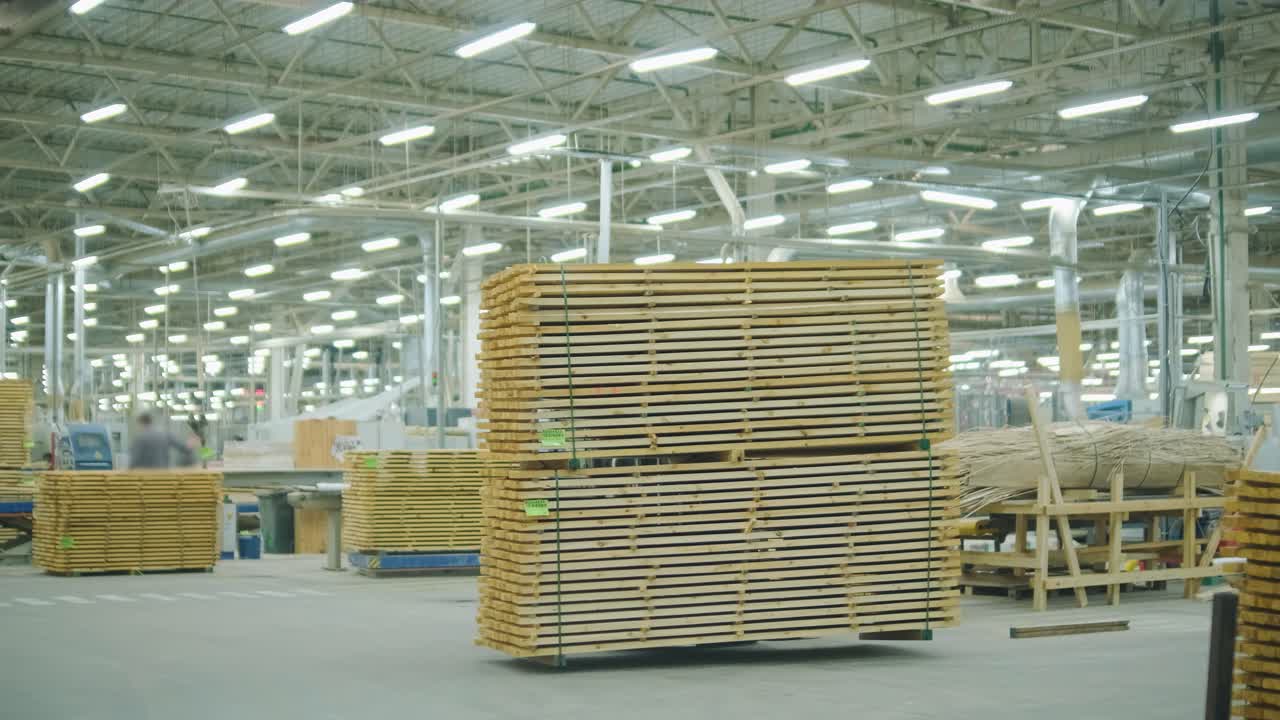 Yellow Forklift Moving Stack of Wooden Planks in a Large Industrial Warehouse