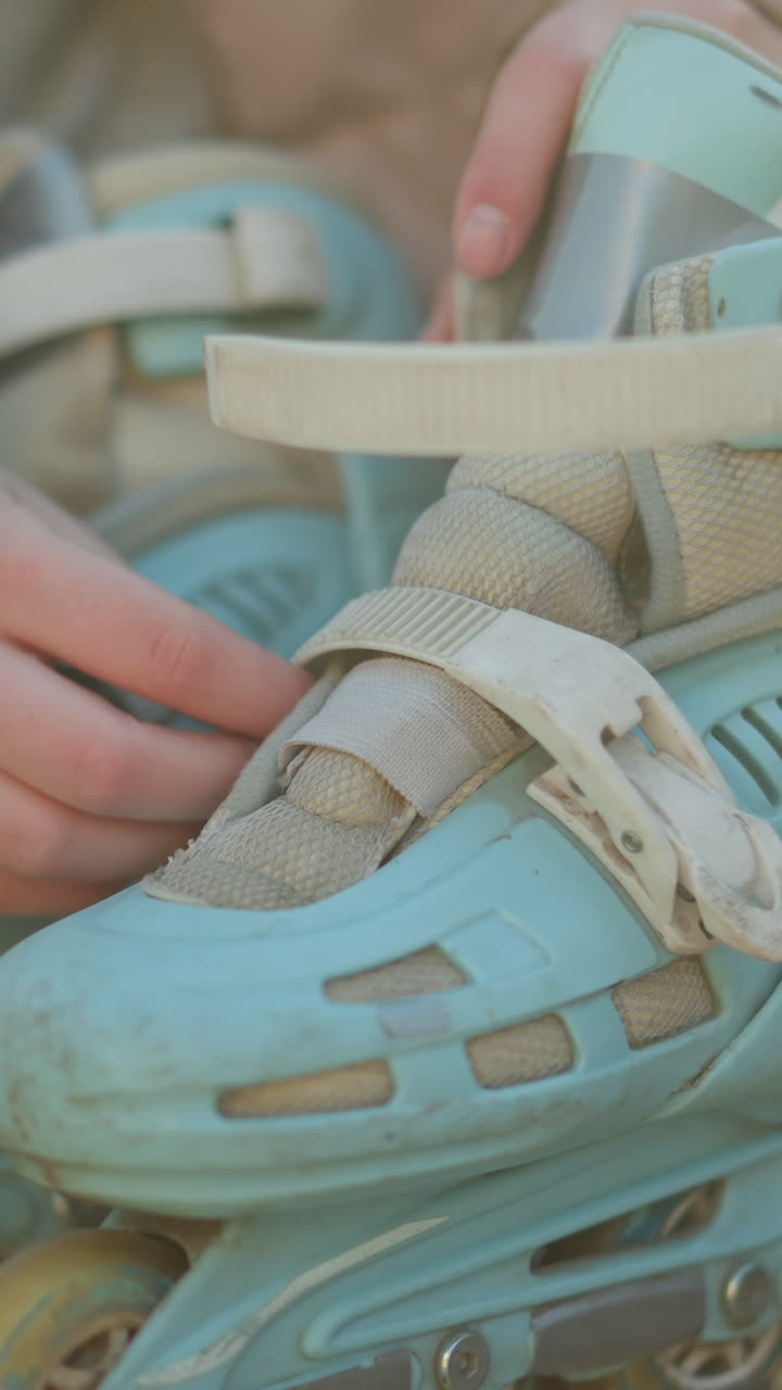 벤치에 앉아있는 복아 재을 입은 사람의 클로즈업, 밝은 파란색 롤러블레이드를 착용하기 위해 준비하고 있습니다. 사람의 손은 을 풀고, 롤러 블레이드를 입을 준비가되어 있습니다.