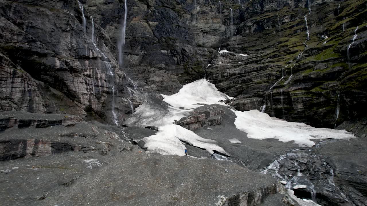 una pared espectacular de cascadas desde el glaciar colgante y el hombre en vigilancia