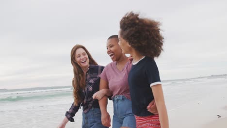 Diverse-group-of-happy-female-friends-walking-on-the-beach-embracing