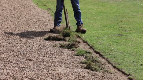 person redefining a gravel path's grassy border.