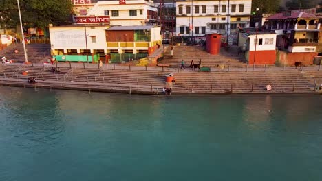 Das-Mit-Religiösen-Tempeln-Gefüllte-Flussufer-Des-Heiligen-Ganges-Am-Abend-Wird-Am-15.-März-2022-In-Rishikesh-Utrakhand,-Indien,-Aus-Der-Luft-Aufgenommen