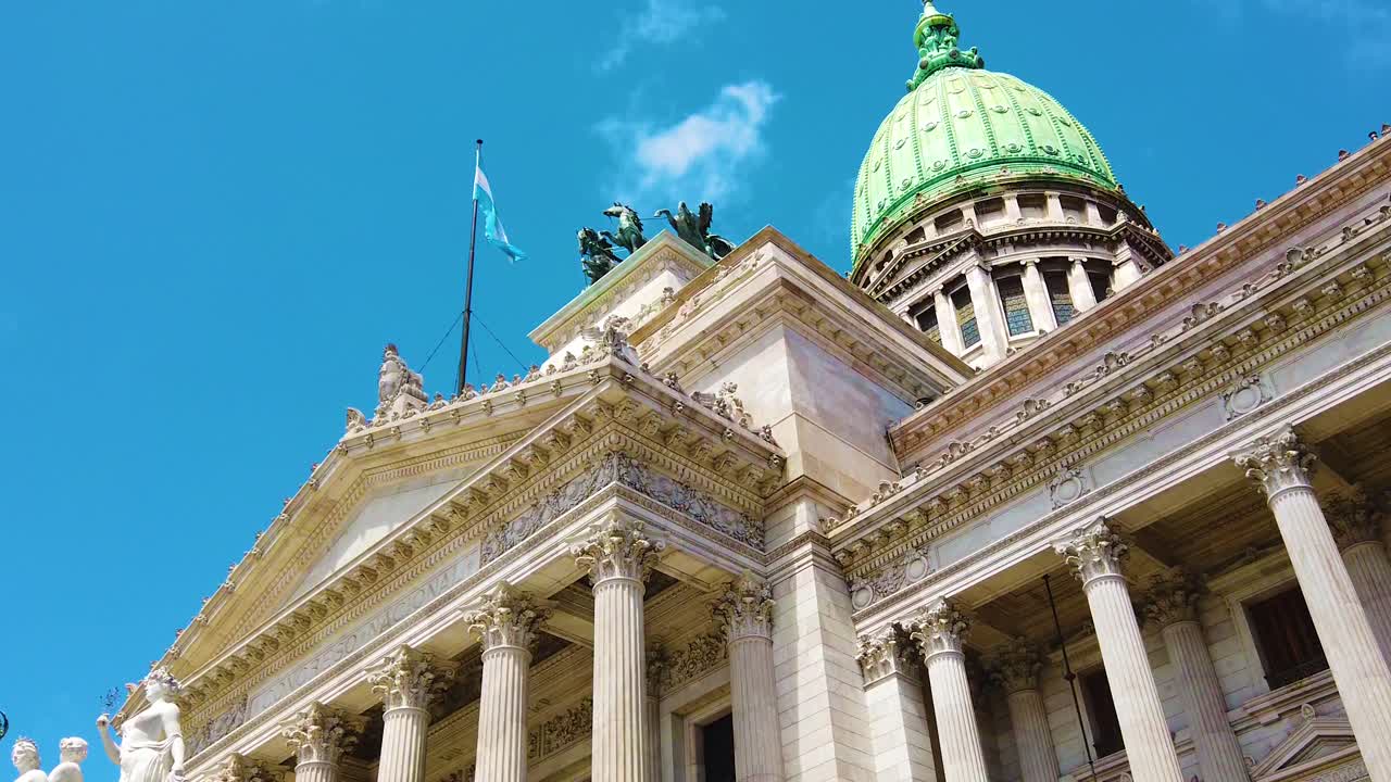 Slow motion low angle view of National Congress of Argentina, National flag waves over summer skyline in Buenos Aires city historical landmark