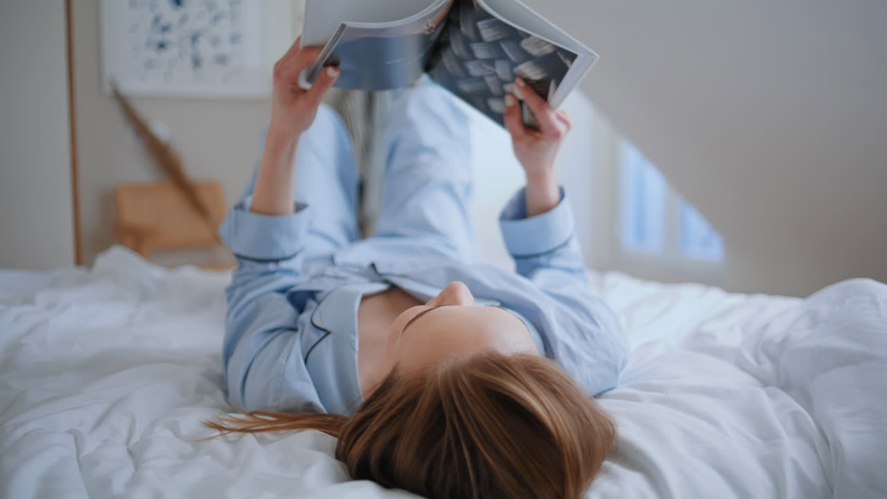 Carefree woman studying book in bedroom closeup. Happy young lady lying home bed