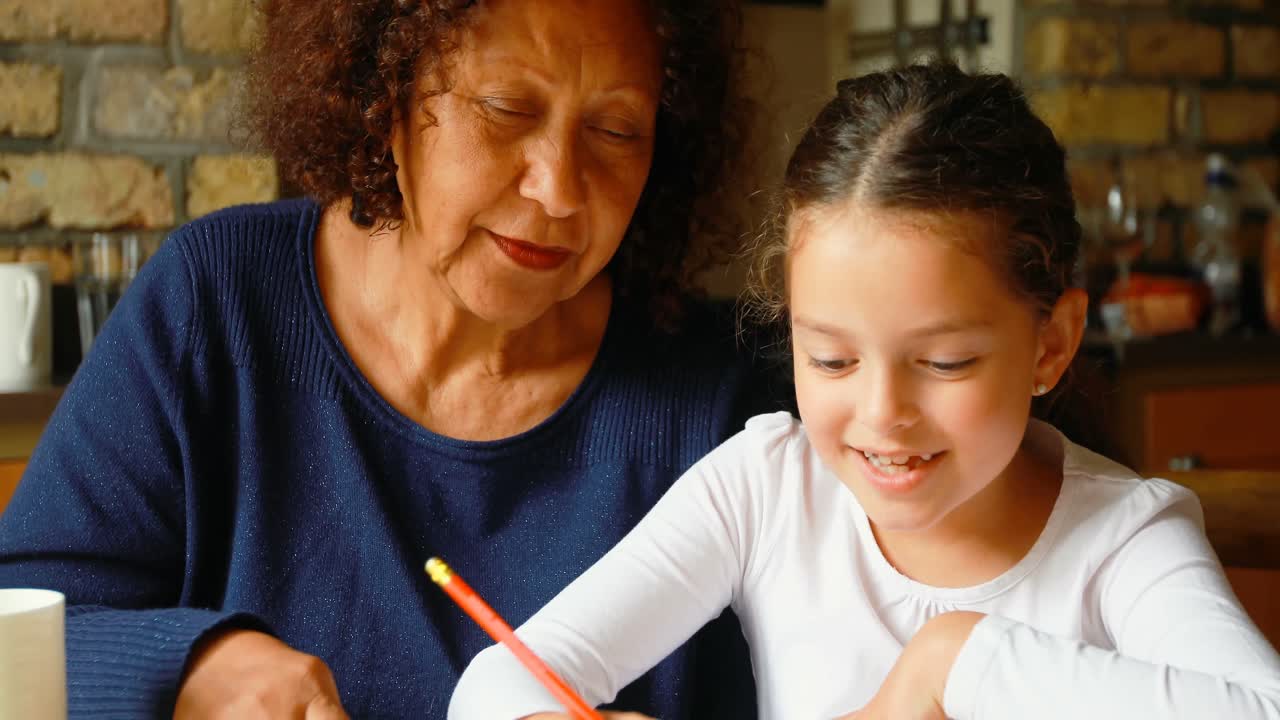 abuela ayudando a su nieta en los estudios en la cocina 4k
