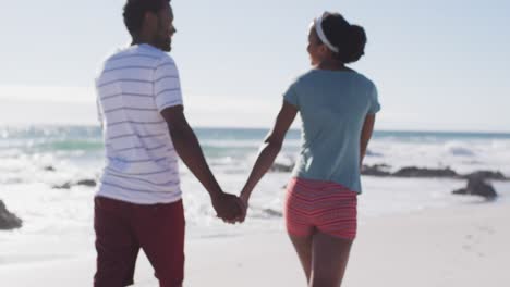 Pareja-Afroamericana-Sonriendo,-Tomados-De-La-Mano-Y-Caminando-Por-La-Playa