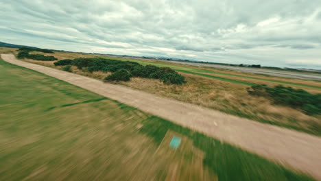 fpv drone flyover golf course, near club house and along green grass of par 5 on ireland links golf course