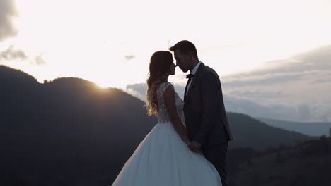 newlyweds silhouettes bride, groom hugging on mountain slope, holding hands, wedding couple family