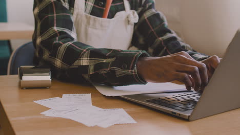 Nahaufnahme-Eines-Nicht-Erkennbaren-Cafébesitzers,-Der-Am-Tisch-Sitzt-Und-Die-Finanzrechnung-Auf-Dem-Laptop-Berechnet-1