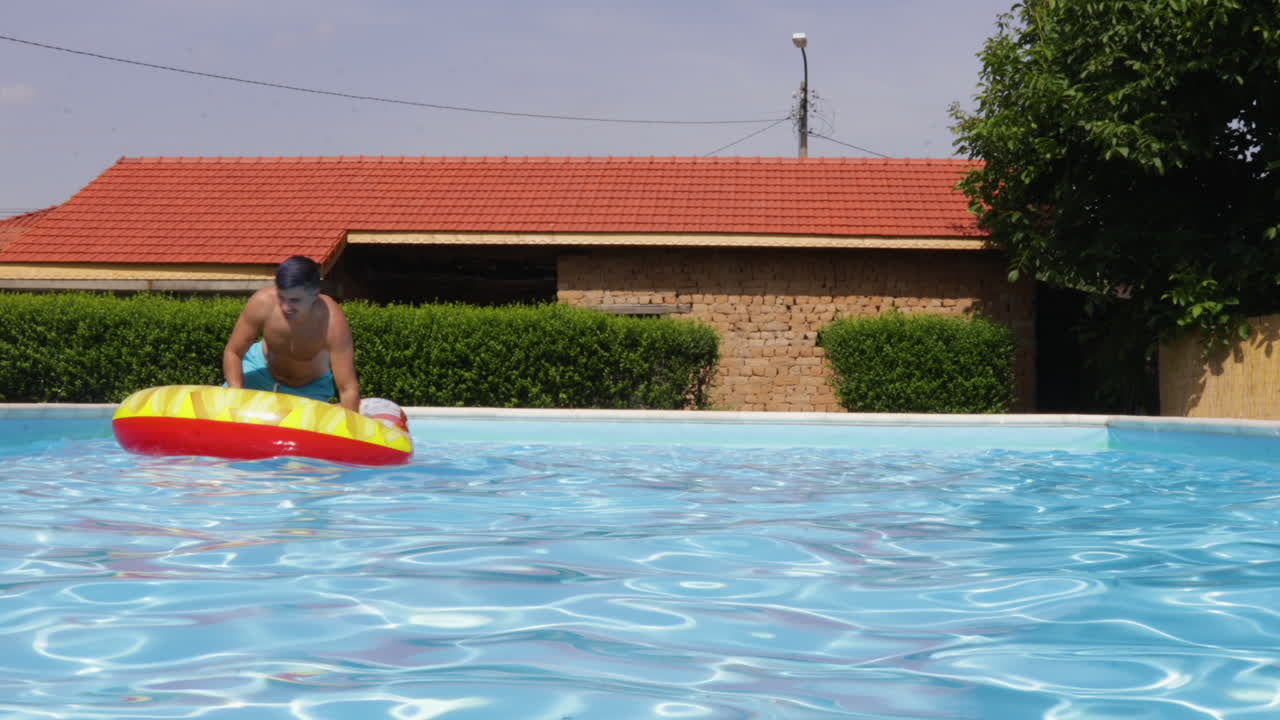 Male Model Riding A Inflatable Floatie In A Outdoor Swimming Pool During Summer.