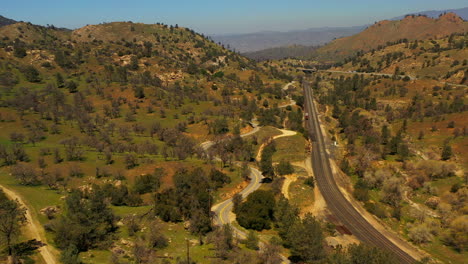 winding roads and train tracks traverse the southern california landscape in spring - aerial view