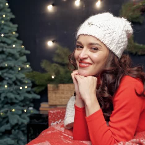 portrait of a beautiful woman on bed. smiling young female having fun at home on christmas tree background. positive girl looking at camera at new year.