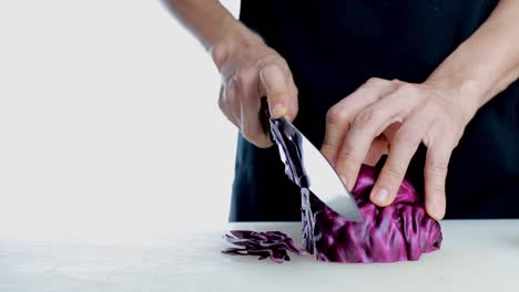 4k women hand cutting fresh red cabbage on cutting board. female hand slices raw red cabbage into little slide with knife on cutting board. healthy food concept.