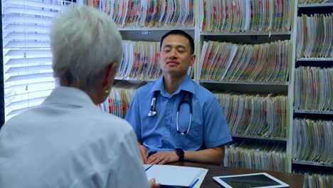 young asian male doctor and senior patient interacting with each other at clinic 4k