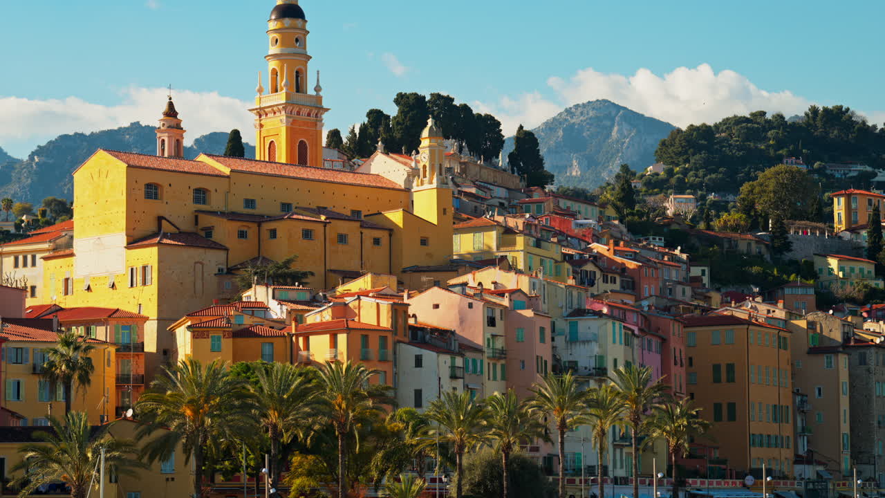 Distant view of the St Michel Basilica surrounded by colourful buildings, Menton, France