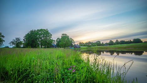 Malerische-Ferienhäuser-An-Einem-Fluss-Und-Einer-Wiese,-Zeitraffer-Von-Der-Morgendämmerung-Bis-Zur-Abenddämmerung