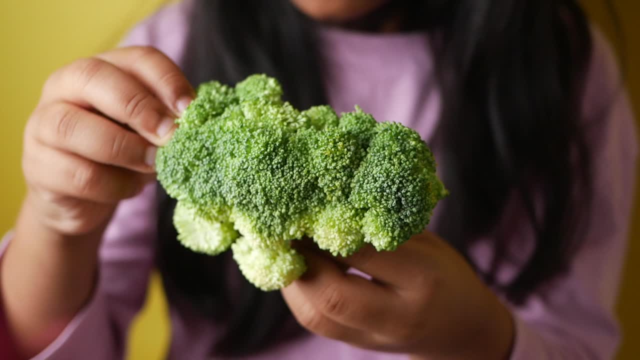 Child holding a head of broccoli